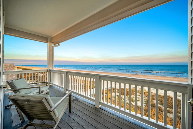 deck at dusk featuring a water view and a view of the beach