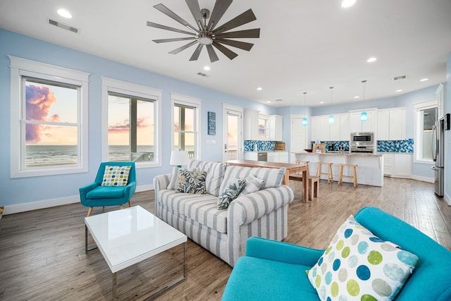 living room featuring light wood-style floors, recessed lighting, visible vents, and baseboards