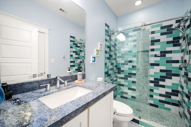 bathroom featuring toilet, vanity, a shower stall, and visible vents