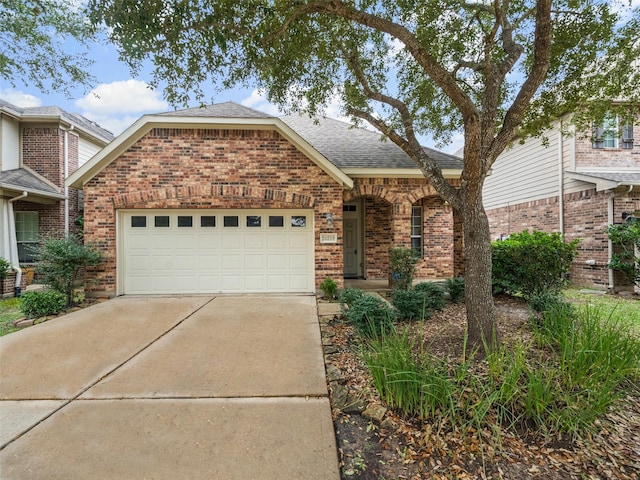 view of front of property with a garage, driveway, a shingled roof, and brick siding