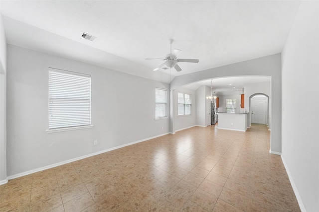 24510 Foxberry Glen Ln, Katy, TX 77494 - unfurnished living room featuring ceiling fan with notable chandelier, baseboards, visible vents, and arched walkways