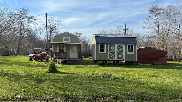 view of front of home featuring a storage shed, a gambrel roof, metal roof, an outdoor structure, and a front lawn