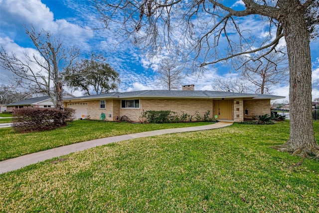 view of front of property with a front lawn, a chimney, an attached garage, and brick siding