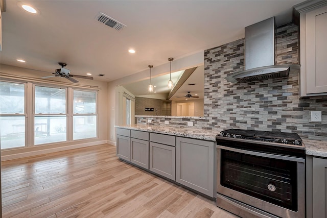 kitchen featuring gray cabinets, visible vents, stainless steel range with gas stovetop, light stone countertops, and wall chimney exhaust hood