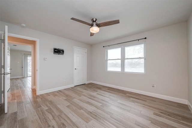 empty room with light wood-type flooring, ceiling fan, and baseboards