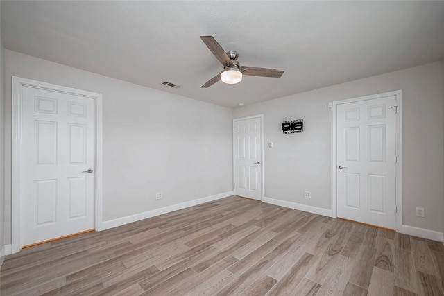 spare room featuring light wood finished floors, a ceiling fan, visible vents, and baseboards