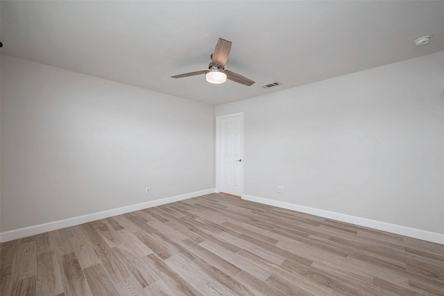 empty room with a ceiling fan, visible vents, light wood-style flooring, and baseboards