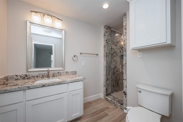 bathroom with toilet, a shower stall, wood finished floors, and vanity