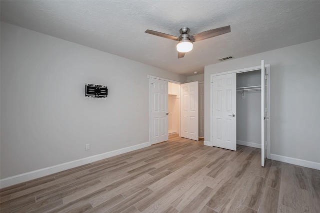 unfurnished bedroom with a textured ceiling, visible vents, baseboards, a closet, and light wood finished floors