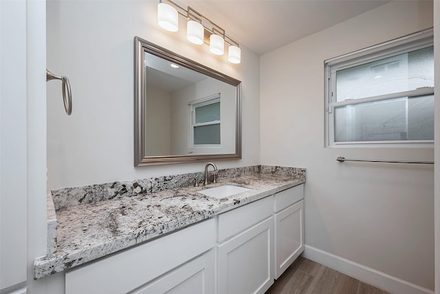 bathroom featuring baseboards, wood finished floors, and vanity