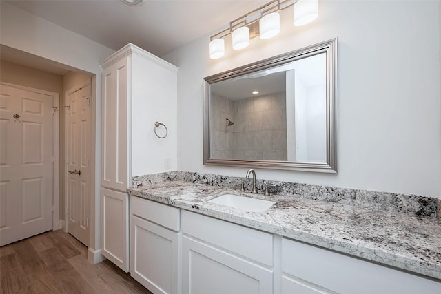 bathroom with vanity, a tile shower, a closet, and wood finished floors