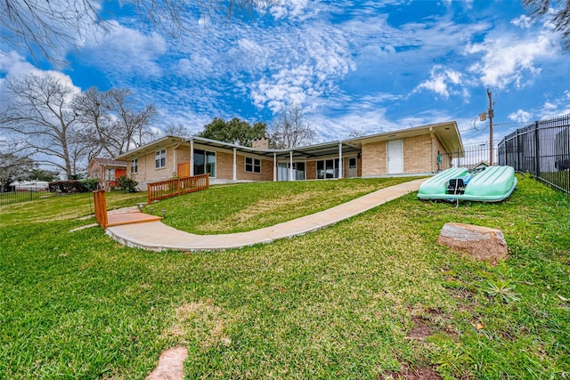 view of front facade with brick siding, a front yard, and fence