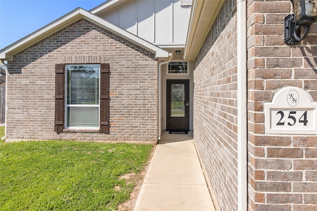 entrance to property with brick siding, board and batten siding, and a lawn