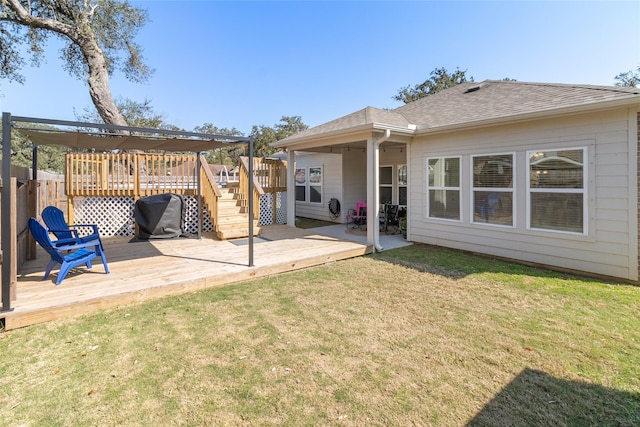 rear view of house featuring a shingled roof, a lawn, a deck, and fence