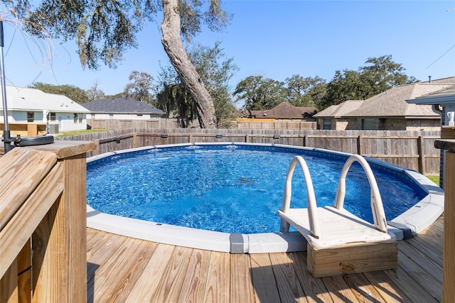 view of swimming pool featuring a residential view, a fenced in pool, a wooden deck, and a fenced backyard