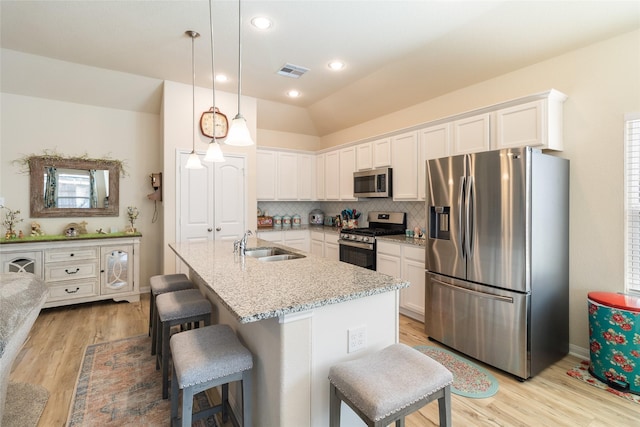 kitchen with visible vents, vaulted ceiling, decorative backsplash, a kitchen breakfast bar, and stainless steel appliances