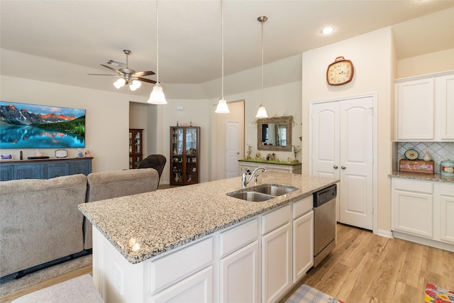 kitchen with light wood finished floors, open floor plan, dishwasher, decorative backsplash, and a sink