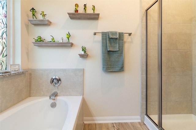 full bathroom featuring baseboards, a garden tub, wood finished floors, and a shower stall