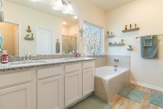 full bath with a sink, a garden tub, wood finished floors, and a shower stall