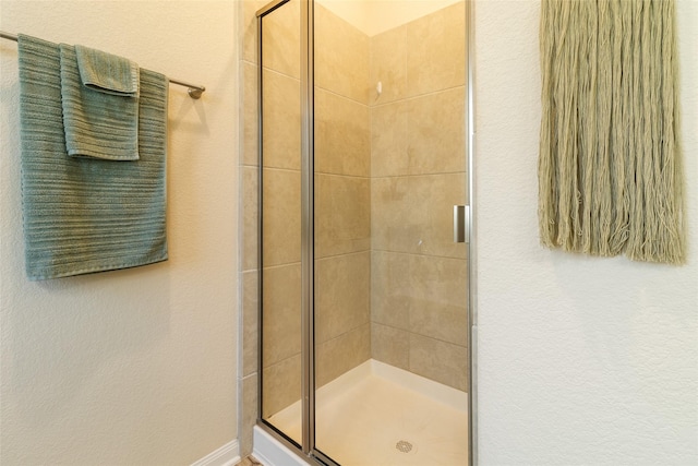 full bath with a shower stall and a textured wall