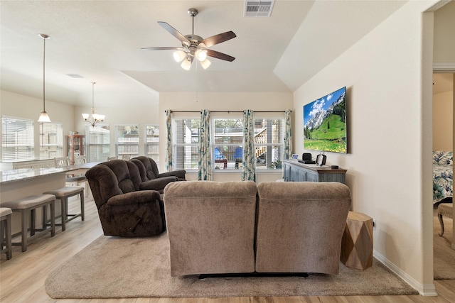 living room featuring visible vents, ceiling fan with notable chandelier, wood finished floors, baseboards, and vaulted ceiling