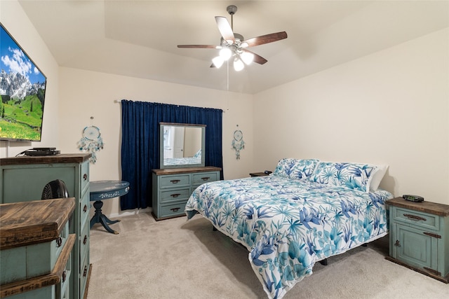 bedroom with ceiling fan, a tray ceiling, and light carpet