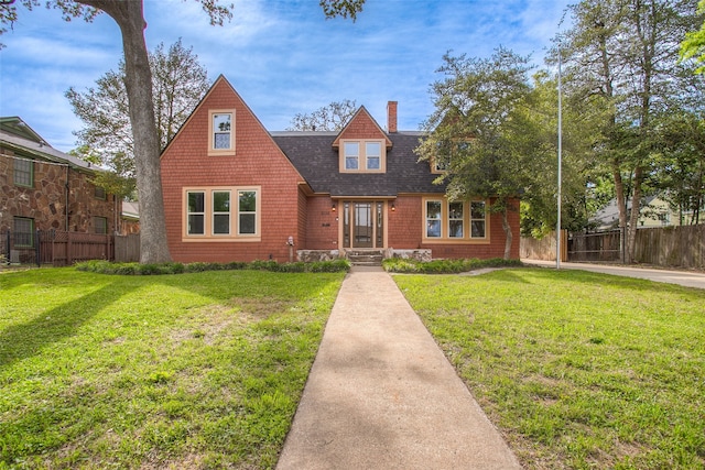 view of front of house featuring roof with shingles, a front lawn, a chimney, and fence