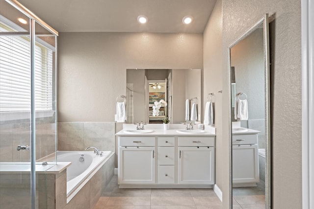 full bathroom with a sink, double vanity, a garden tub, and tile patterned floors