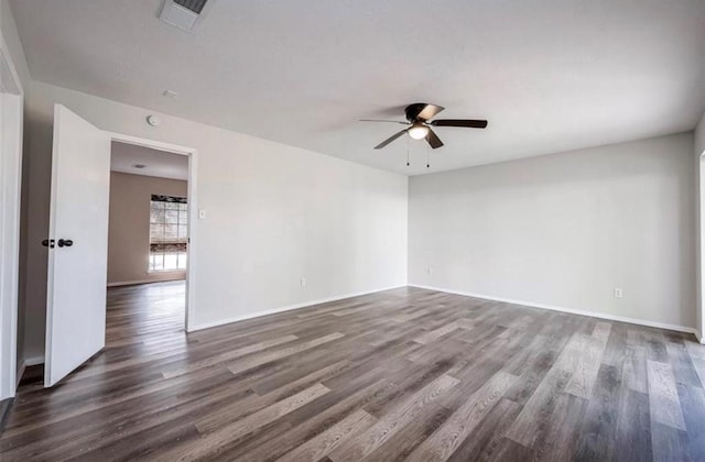 unfurnished room featuring dark wood-style floors, ceiling fan, visible vents, and baseboards