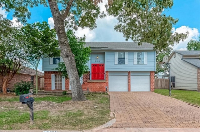 bi-level home with a garage, decorative driveway, and brick siding