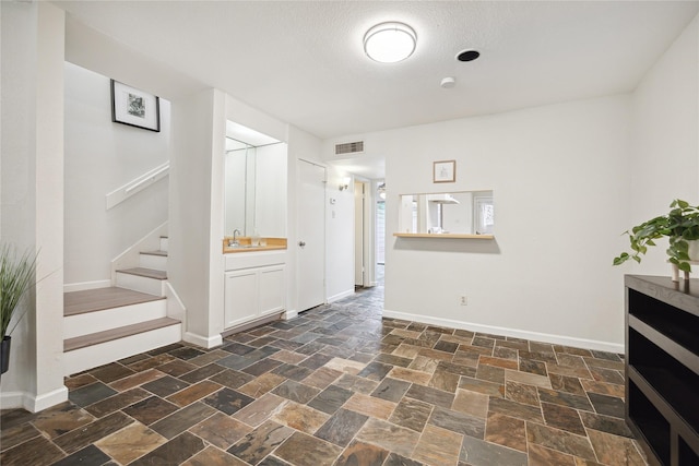 interior space with stairs, stone finish flooring, baseboards, and a sink