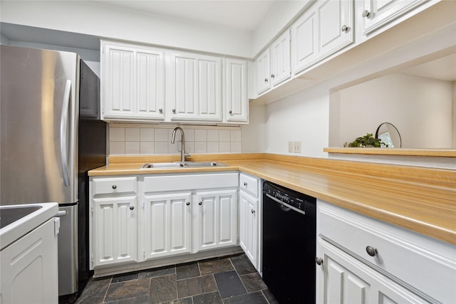 kitchen with stone finish floor, a sink, freestanding refrigerator, white cabinets, and dishwasher