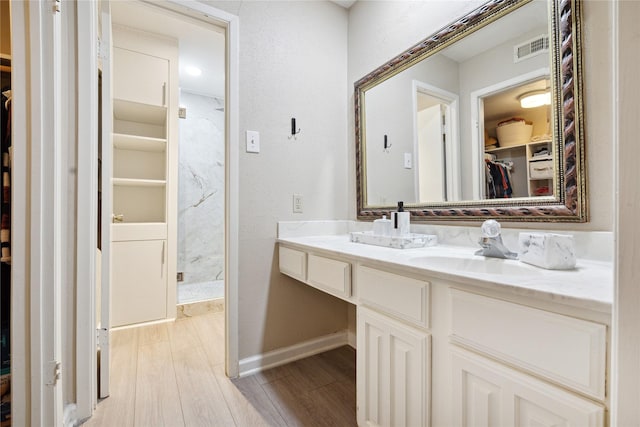 bathroom featuring baseboards, visible vents, wood finished floors, a spacious closet, and vanity