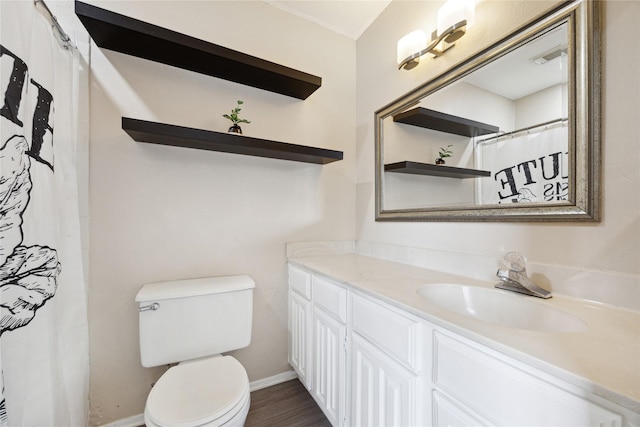 bathroom with visible vents, toilet, vanity, wood finished floors, and baseboards