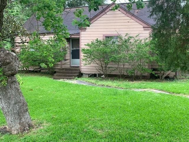 rear view of property with a lawn, roof with shingles, and entry steps