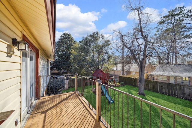 wooden deck featuring a playground, a lawn, and fence