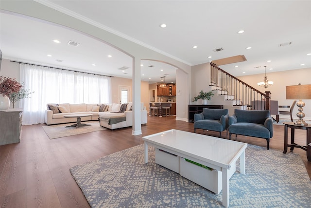 living area with arched walkways, recessed lighting, ornamental molding, stairway, and dark wood-style floors