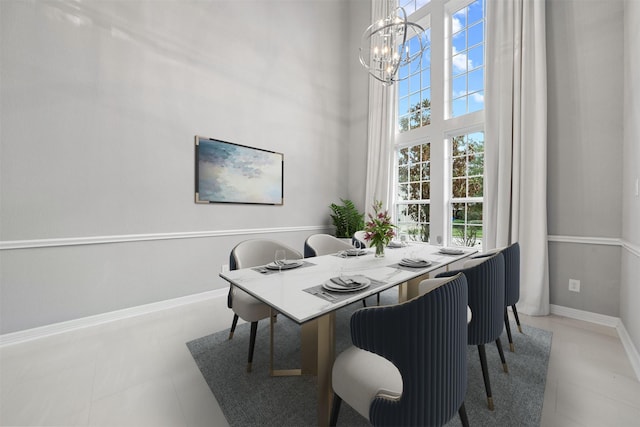 dining room with a high ceiling, a notable chandelier, plenty of natural light, and baseboards