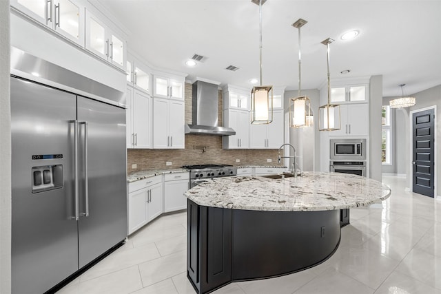 kitchen with glass insert cabinets, white cabinets, a sink, built in appliances, and wall chimney exhaust hood