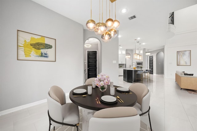 dining room with arched walkways, light tile patterned flooring, recessed lighting, visible vents, and baseboards