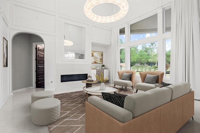 living room with arched walkways, built in shelves, a high end fireplace, and a towering ceiling