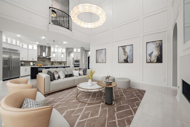 living area with light tile patterned floors, a high ceiling, and a decorative wall