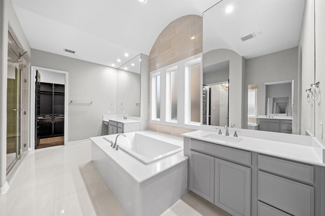 bathroom featuring lofted ceiling, recessed lighting, two vanities, a sink, and visible vents