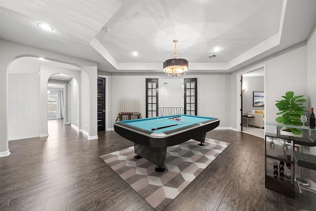 rec room with baseboards, arched walkways, a raised ceiling, dark wood-type flooring, and a chandelier