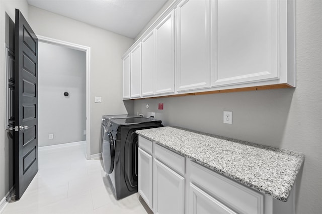 laundry area with light tile patterned flooring, washing machine and dryer, cabinet space, and baseboards