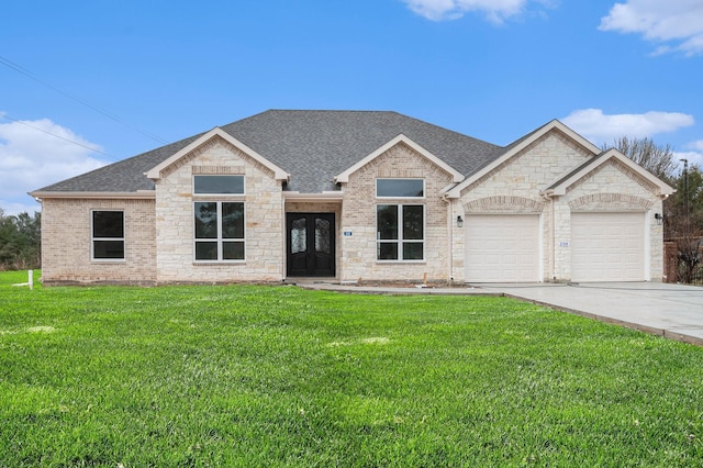 view of front of home featuring a garage, a shingled roof, brick siding, driveway, and a front yard