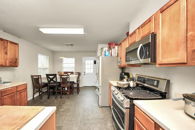 kitchen with visible vents, brown cabinetry, appliances with stainless steel finishes, decorative light fixtures, and light countertops