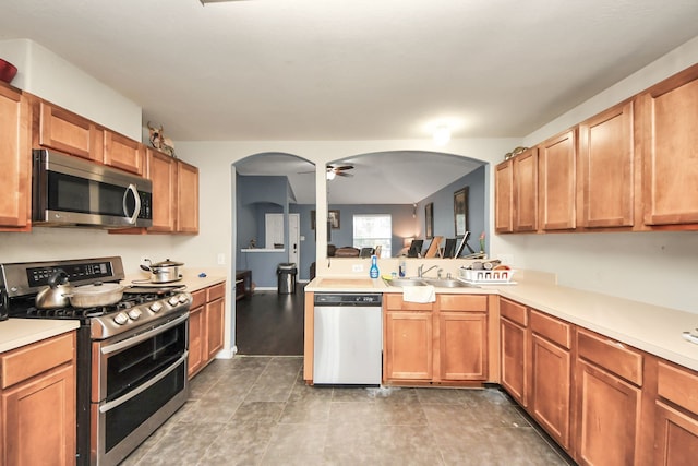 kitchen with a sink, ceiling fan, stainless steel appliances, and light countertops