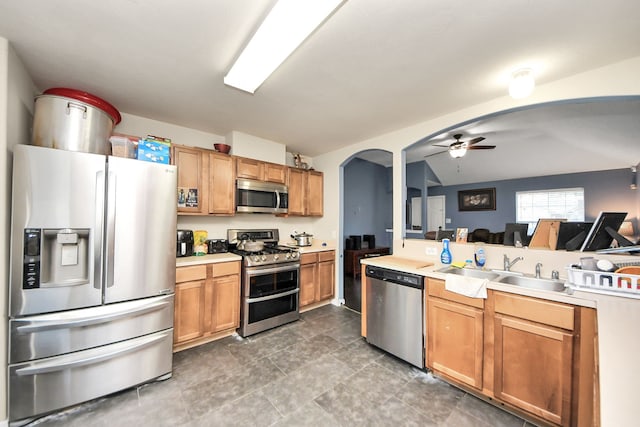 kitchen featuring arched walkways, stainless steel appliances, a sink, and light countertops