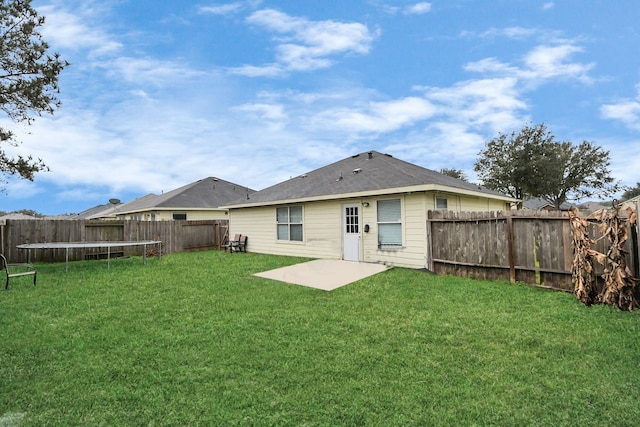 back of house featuring a patio area, a fenced backyard, a trampoline, and a yard